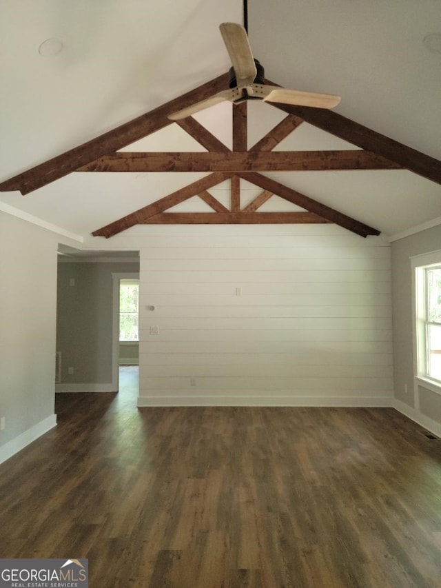 unfurnished room with wood walls, lofted ceiling with beams, dark hardwood / wood-style floors, and plenty of natural light