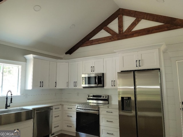 kitchen featuring sink, white cabinetry, stainless steel appliances, and lofted ceiling with beams