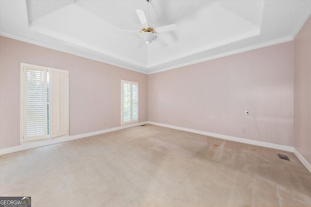 carpeted spare room featuring ceiling fan, ornamental molding, and a tray ceiling