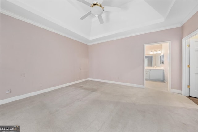 spare room featuring light carpet, crown molding, a tray ceiling, and ceiling fan