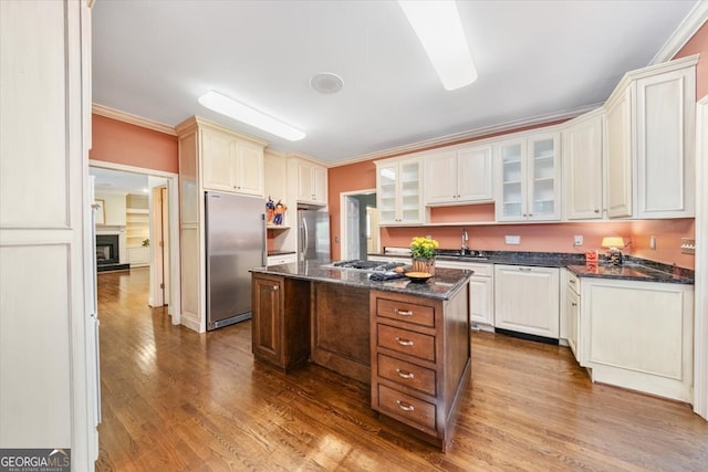 kitchen featuring a kitchen island, dark stone countertops, ornamental molding, hardwood / wood-style floors, and appliances with stainless steel finishes