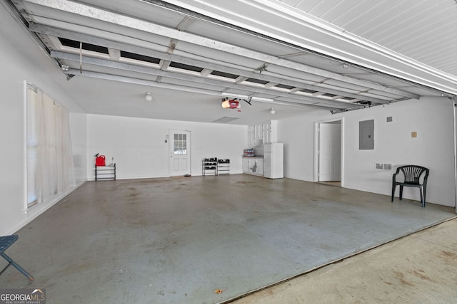 garage featuring electric panel, white fridge, and a garage door opener