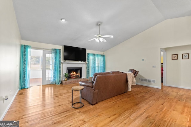 living room with light hardwood / wood-style floors, lofted ceiling, a fireplace, and ceiling fan