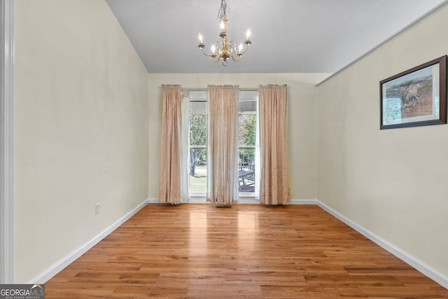 spare room with an inviting chandelier and light wood-type flooring