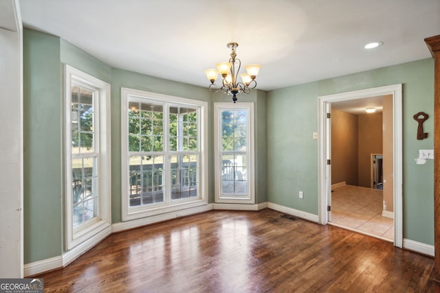 unfurnished dining area featuring a notable chandelier and dark hardwood / wood-style floors