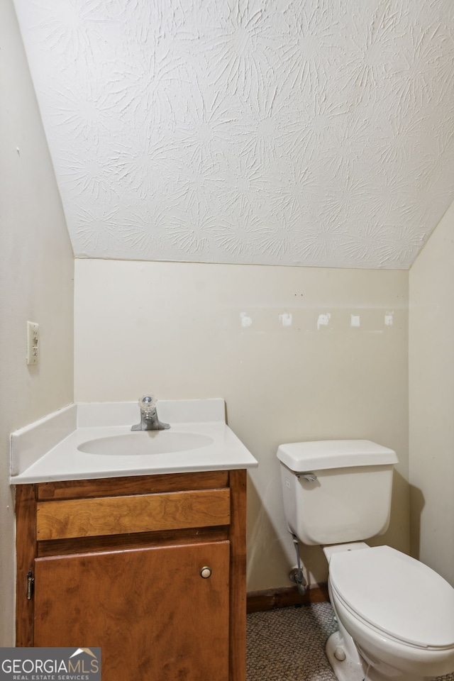 bathroom with vanity, toilet, and vaulted ceiling