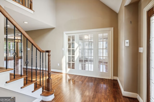 entryway with a notable chandelier, a healthy amount of sunlight, wood-type flooring, and high vaulted ceiling