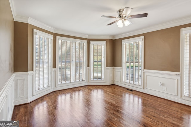 empty room with ornamental molding, hardwood / wood-style flooring, a healthy amount of sunlight, and ceiling fan