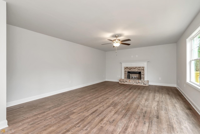 unfurnished living room featuring a fireplace, hardwood / wood-style flooring, a wealth of natural light, and ceiling fan