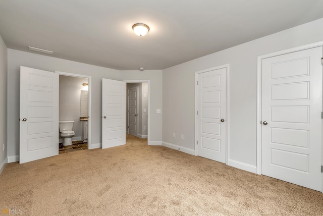 unfurnished bedroom featuring carpet flooring and ensuite bath