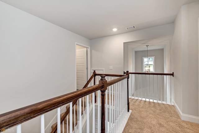 hallway featuring carpet flooring and a notable chandelier