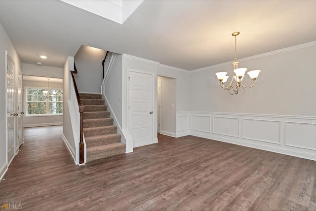 unfurnished dining area with dark hardwood / wood-style floors, an inviting chandelier, and ornamental molding