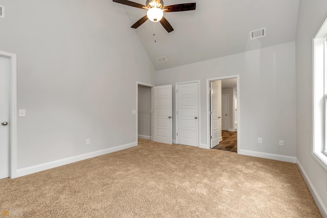 unfurnished bedroom with carpet flooring, ceiling fan, and high vaulted ceiling