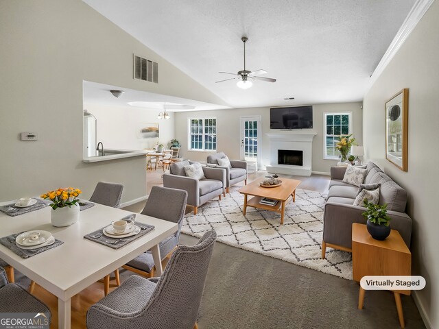 living room with ceiling fan, crown molding, a textured ceiling, and vaulted ceiling