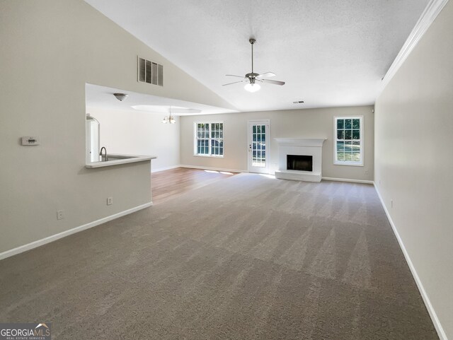 unfurnished living room with carpet floors, high vaulted ceiling, ceiling fan with notable chandelier, and a textured ceiling