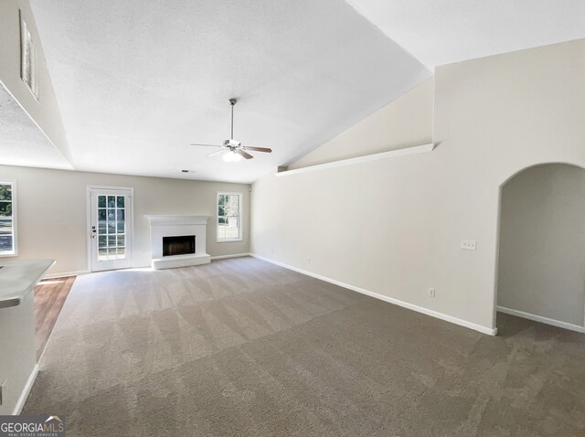 unfurnished living room featuring lofted ceiling, dark carpet, and ceiling fan