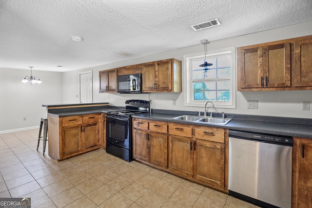 kitchen with kitchen peninsula, sink, black appliances, pendant lighting, and an inviting chandelier