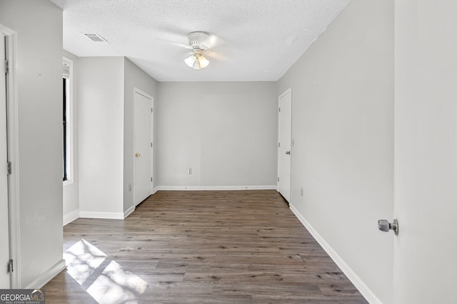 spare room featuring a textured ceiling, wood-type flooring, a healthy amount of sunlight, and ceiling fan