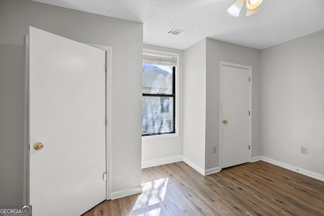 unfurnished bedroom featuring a textured ceiling, wood-type flooring, and ceiling fan