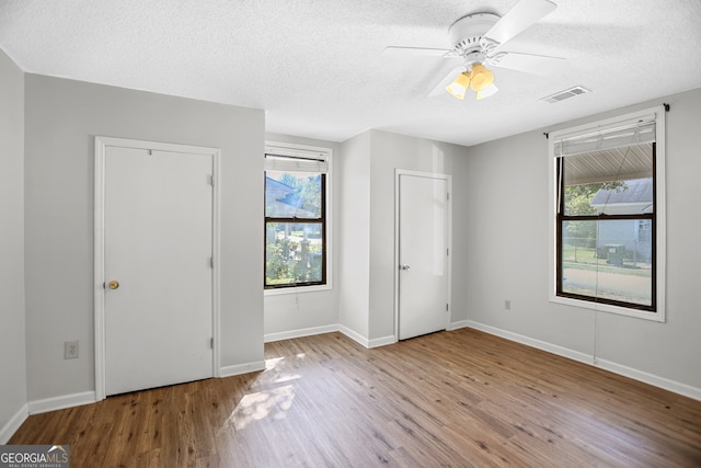 unfurnished bedroom featuring ceiling fan, a textured ceiling, and light hardwood / wood-style floors