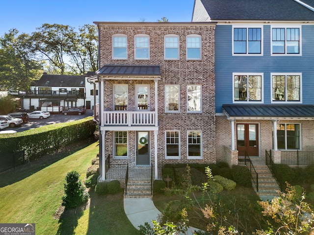 townhome / multi-family property with a balcony and a front lawn