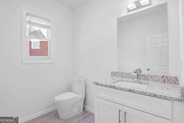 bathroom with toilet, hardwood / wood-style flooring, and vanity