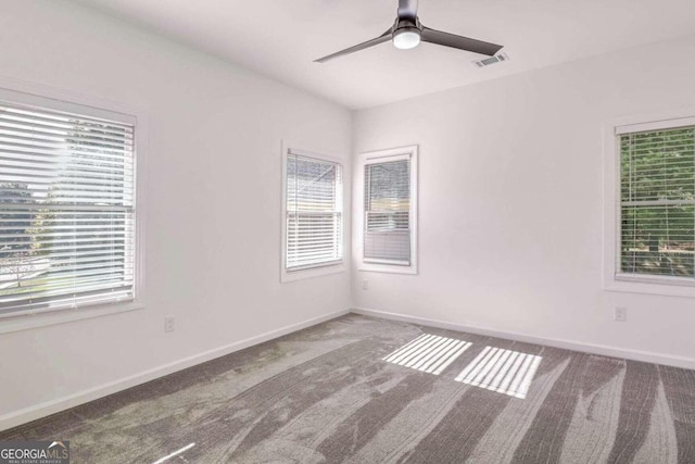 empty room with a wealth of natural light, carpet flooring, and ceiling fan