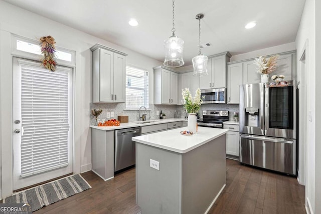 kitchen with sink, a kitchen island, stainless steel appliances, and dark hardwood / wood-style flooring