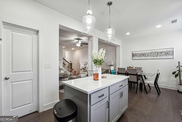 kitchen featuring a kitchen island, dark hardwood / wood-style floors, gray cabinetry, decorative light fixtures, and ceiling fan