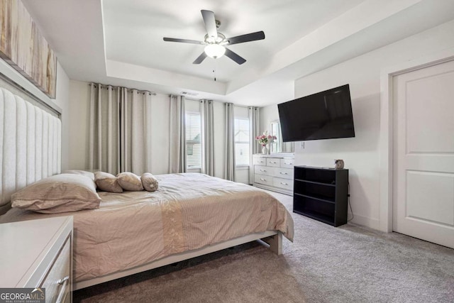 carpeted bedroom featuring ceiling fan and a raised ceiling