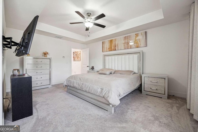 bedroom featuring light carpet, a tray ceiling, and ceiling fan