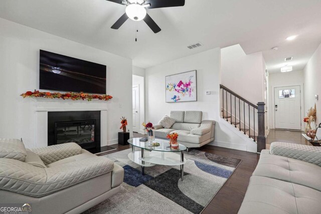 living room featuring dark wood-type flooring and ceiling fan