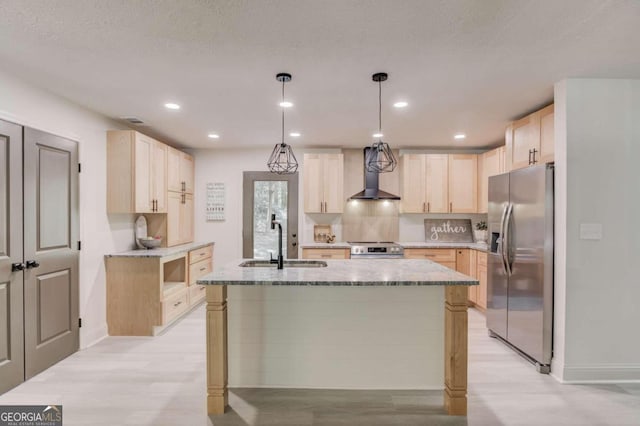 kitchen with a kitchen island with sink, wall chimney exhaust hood, hanging light fixtures, sink, and appliances with stainless steel finishes