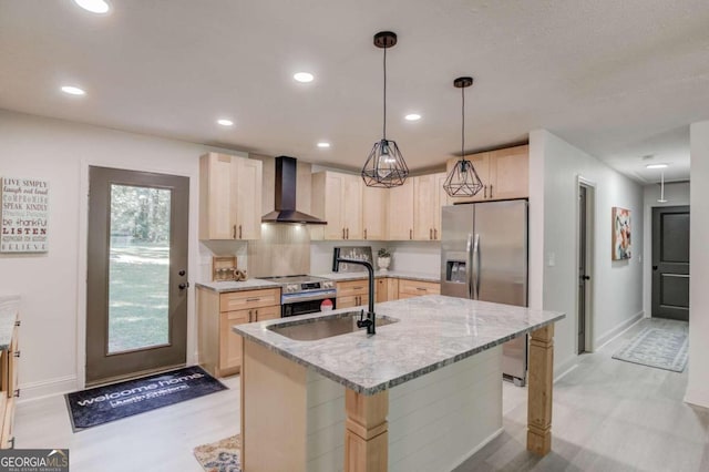 kitchen featuring light stone countertops, wall chimney range hood, stainless steel appliances, light brown cabinets, and a kitchen island with sink