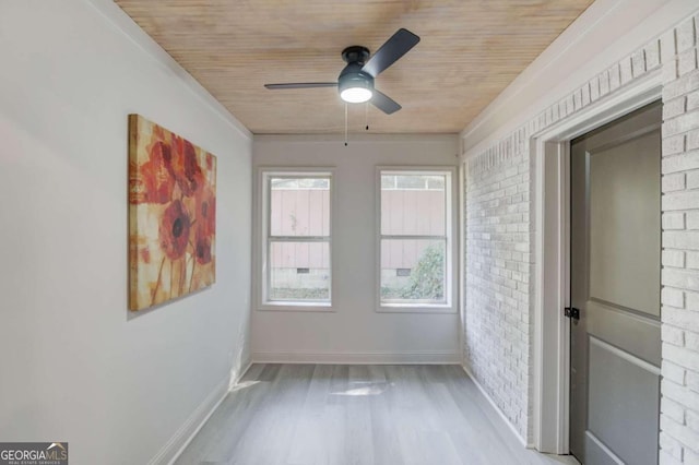 unfurnished room with wood ceiling, brick wall, light wood-type flooring, and ceiling fan