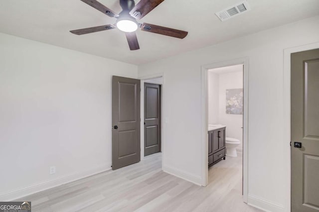 unfurnished bedroom featuring ensuite bath, light wood-type flooring, and ceiling fan