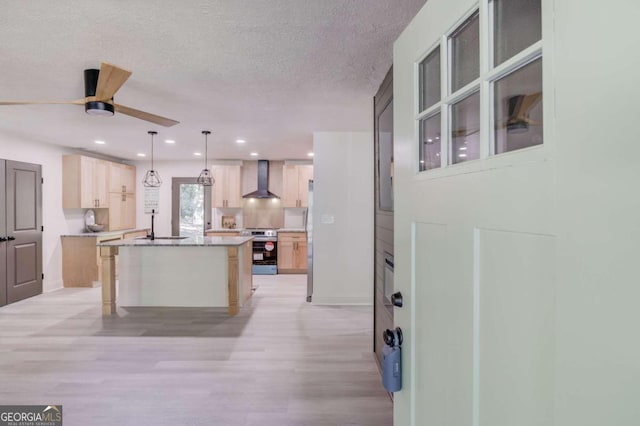 kitchen featuring light brown cabinetry, electric range, a center island, hanging light fixtures, and wall chimney exhaust hood