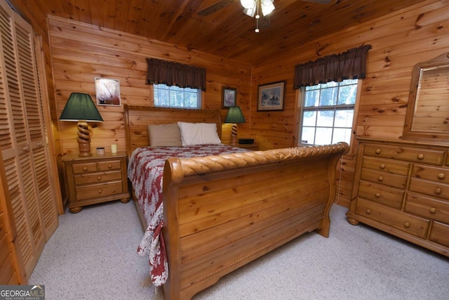 bedroom with ceiling fan, wooden walls, and light colored carpet