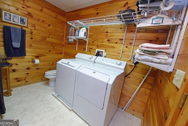 clothes washing area featuring wooden walls and separate washer and dryer