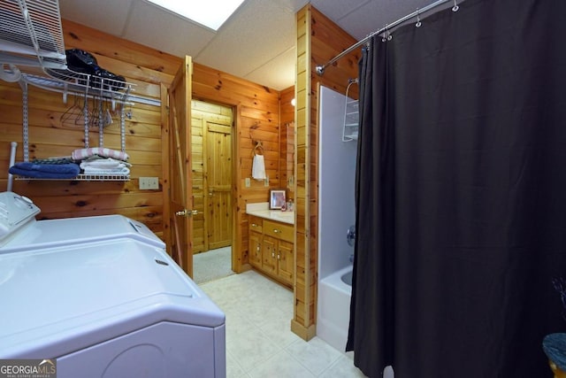 clothes washing area featuring wooden walls and washing machine and clothes dryer