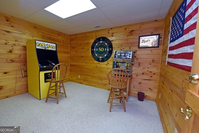 playroom with wood walls, a drop ceiling, and carpet floors