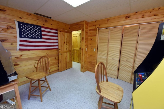 carpeted office with wooden walls and a drop ceiling