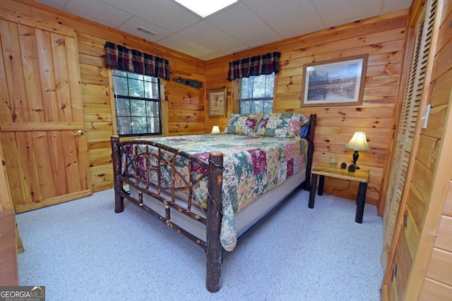 bedroom with light carpet, multiple windows, and wood walls