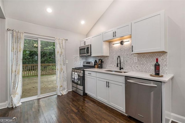 kitchen featuring lofted ceiling, dark wood-type flooring, white cabinetry, appliances with stainless steel finishes, and tasteful backsplash