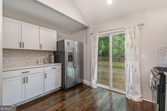 kitchen featuring lofted ceiling, tasteful backsplash, appliances with stainless steel finishes, white cabinetry, and dark wood-type flooring