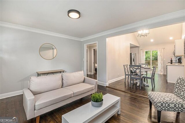 living room with sink, dark hardwood / wood-style flooring, vaulted ceiling, crown molding, and a notable chandelier