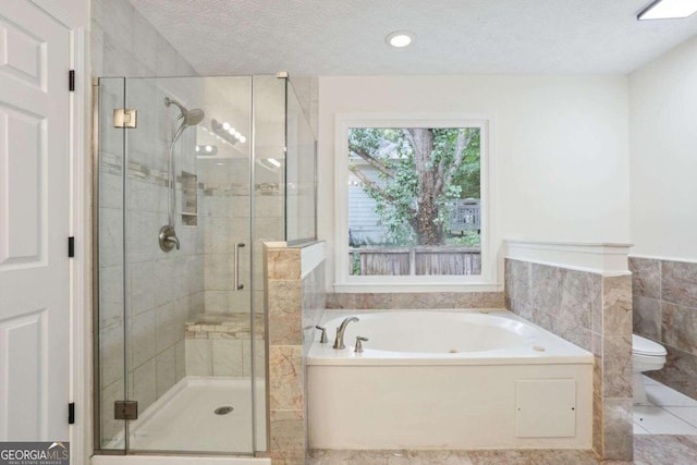 bathroom with a textured ceiling, separate shower and tub, toilet, tile walls, and tile patterned flooring