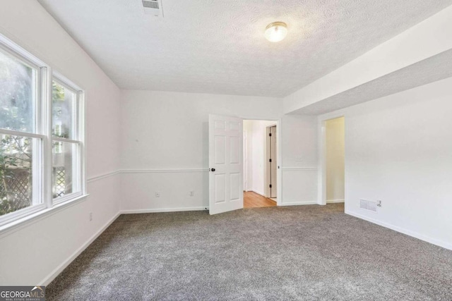 spare room featuring a textured ceiling and carpet floors