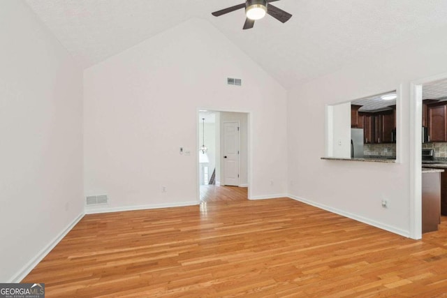 unfurnished living room with light hardwood / wood-style floors, high vaulted ceiling, a textured ceiling, and ceiling fan