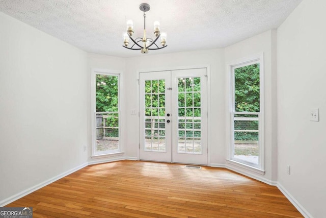 interior space featuring french doors, a notable chandelier, hardwood / wood-style flooring, and a textured ceiling